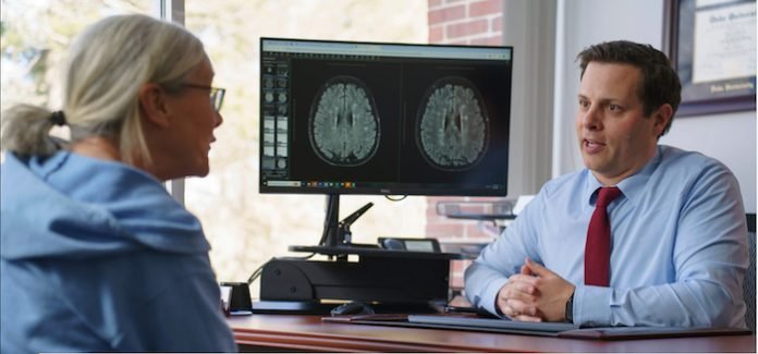 Screenshot Top: Neurologist Andrew Bouley (right) speaks with his patient Emily Wheeler while they look at her brain scans in his office in Massachusetts. Visual: Jodi Hilton for Undark