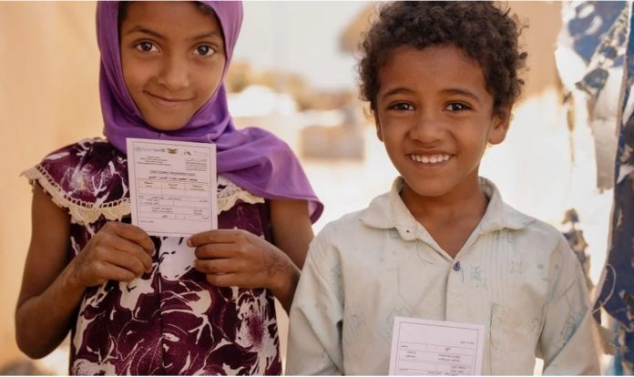 Two children hold their vaccination cards after receiving the oral cholera vaccine in Sannah camp in Al Dhale'e, Yemen. Photo: WHO EMRO